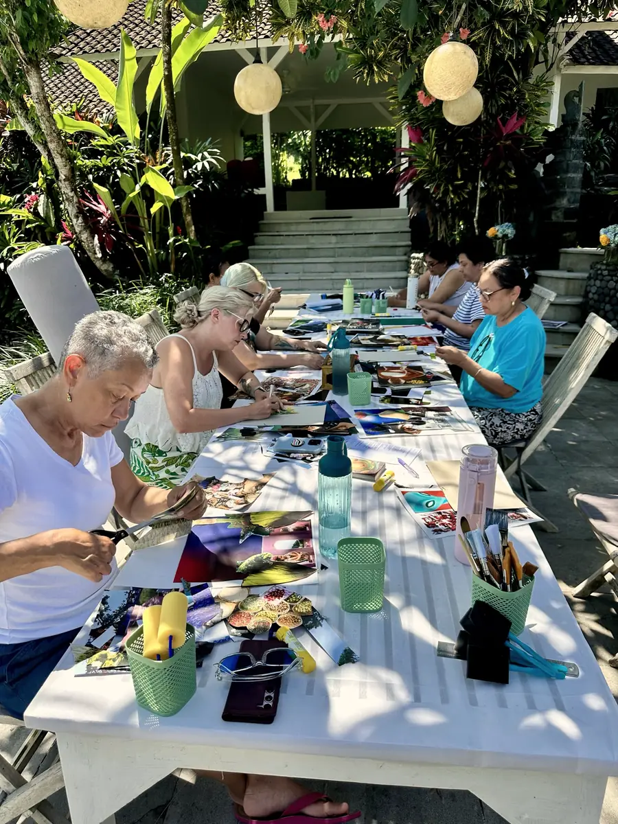 The long collage table at Ana's Bali retreat, with women cutting magazines under paper lanterns